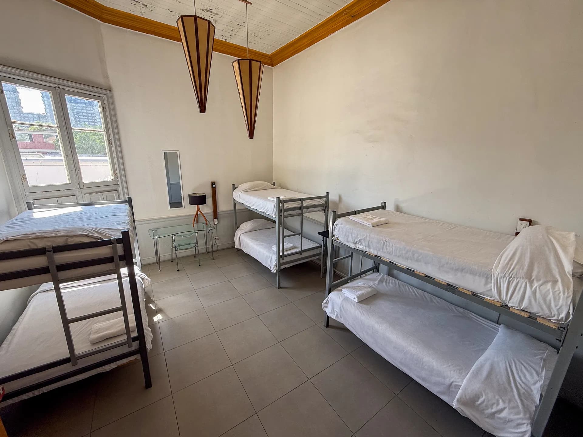 Dormitory room at Happy House Santiago with bunk beds, personal lockers and high ceilings with art deco lamps